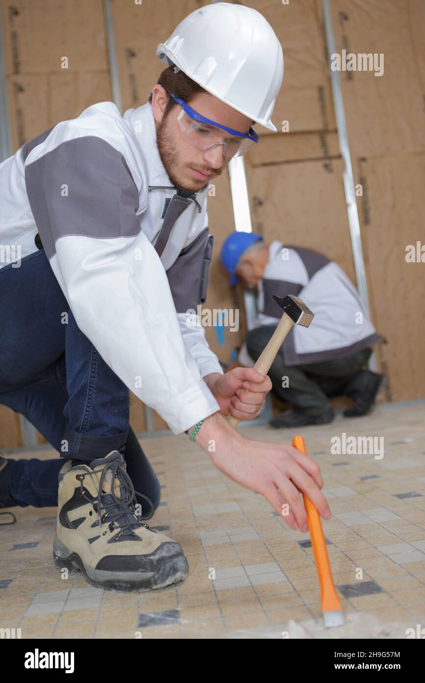 constructon worker removing old floor tiles Stock Photo