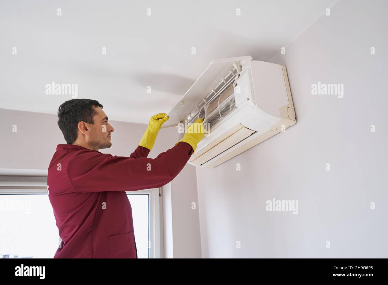 Concentrated cleaner in rubber gloves cleaning air-conditioning unit Stock Photo