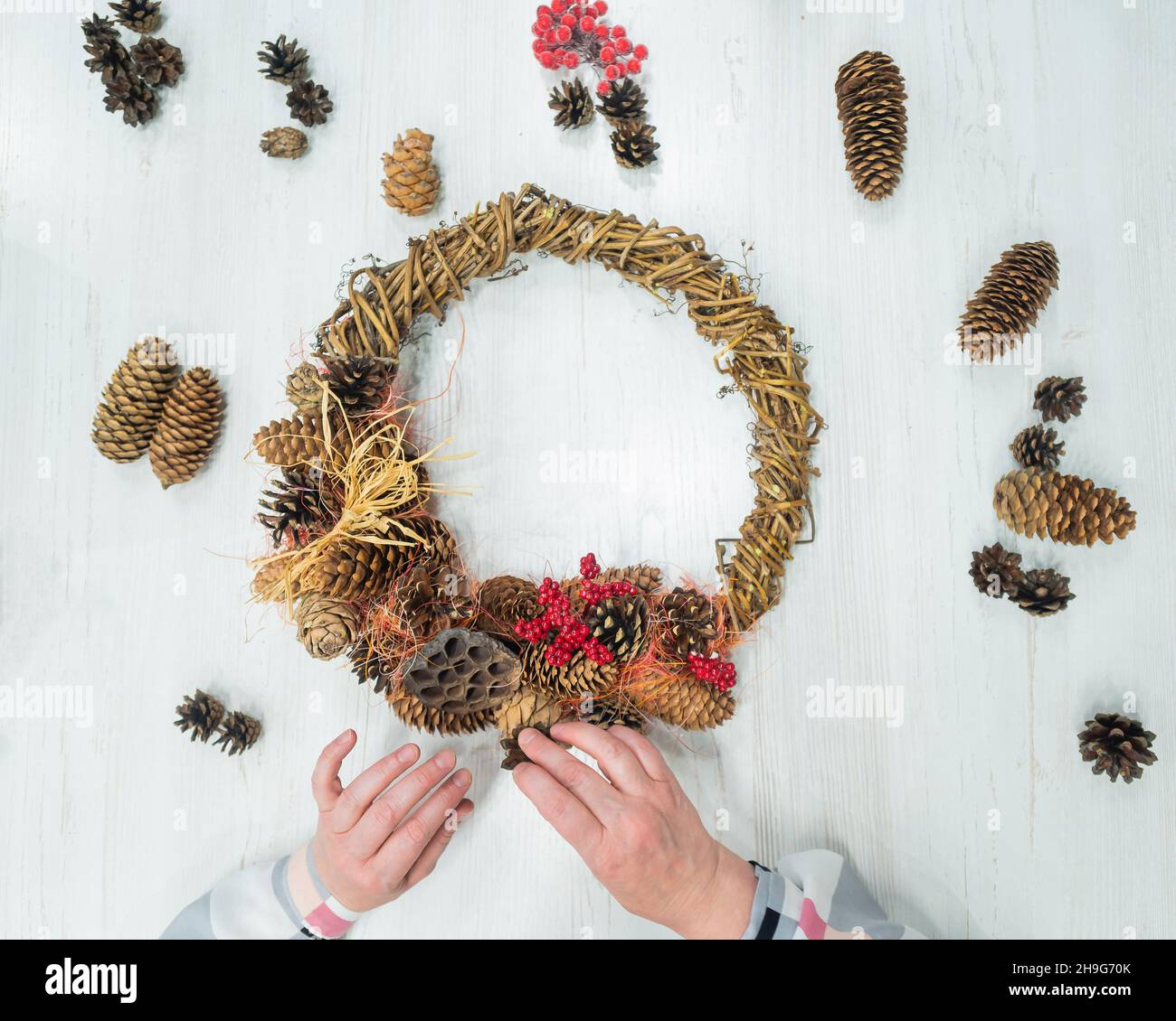 Top view of female hands making a wreath for christmas. An elderly woman makes decorations for the New Year with her own hands Stock Photo
