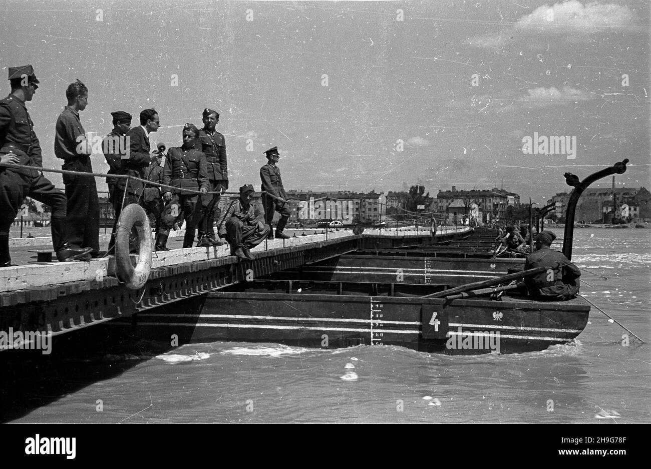 Warszawa, 1948-06. Przygotowania przed nadejœciem kulminacyjnej fali powodziowej na Wiœle. Zabezpieczanie mostu pontonowego. Nz. sprawozdawca radiowy relacjonuje stan przygotowañ, przeprowadza wywiad z saperami. Dok³adny dzieñ wydarzenia nieustalony.  as  PAP      Warsaw, June 1948. Preparations ahead of flood-wave peak on the Vistula River. Work to secure a pontoon bridge against flood. Pictured: a radio commentator reporting on the preparations, interviewing sappers.  as  PAP Stock Photo