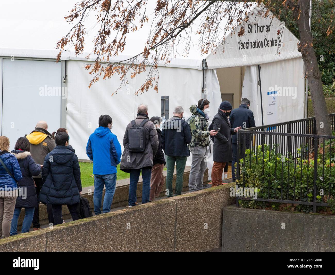 People queue outside St Thomas Hospital, South London to receive the Covid booster jab as the Omnicron variant takes hold in the UK. Stock Photo