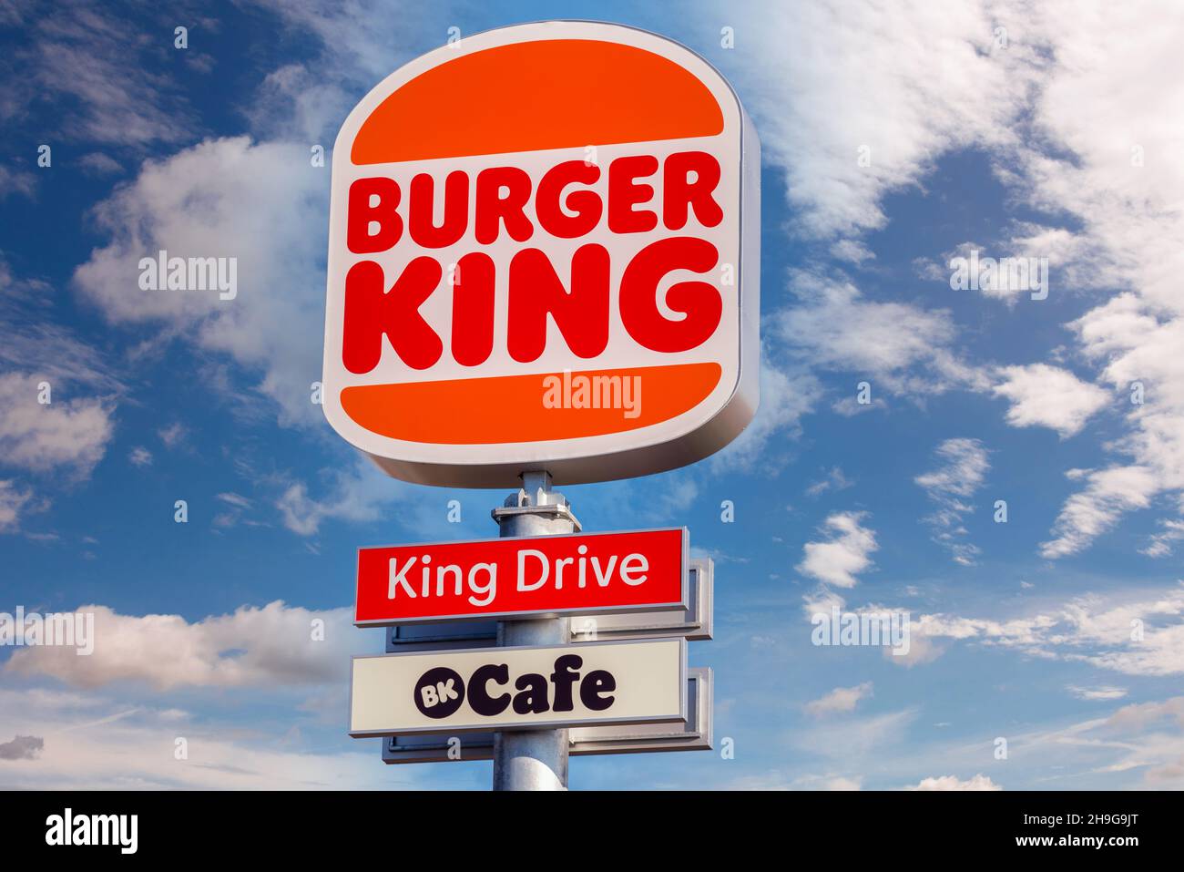 Moncalieri, Turin, Italy - December 6, 2021:  sign post with new logo of Burger King Restaurant with King Drive on blue sky with clouds in via Fortuna Stock Photo