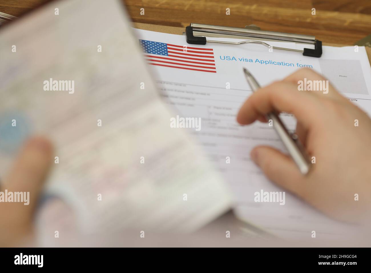 Person filling visa application forms holding personal passport Stock Photo