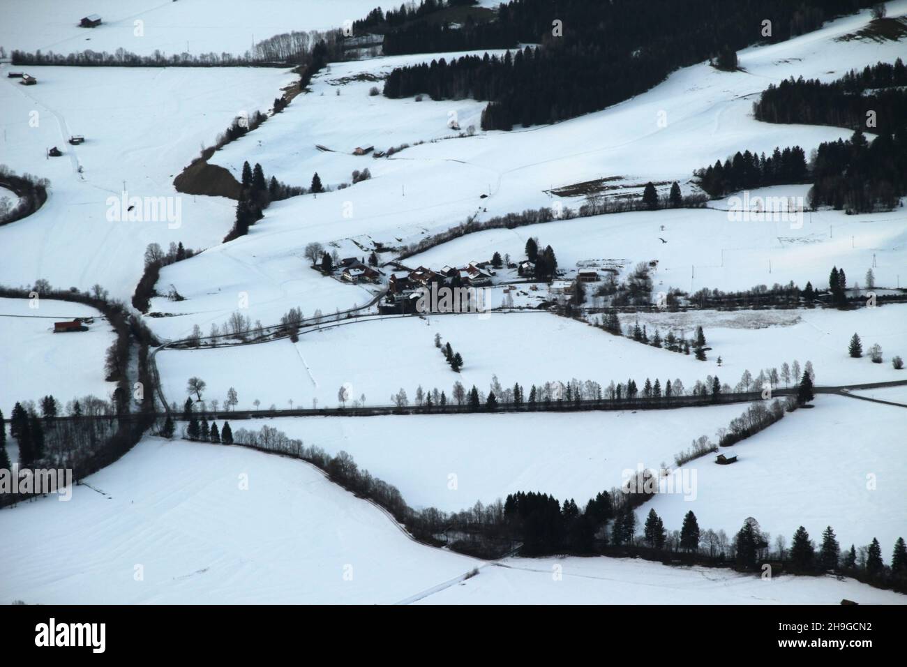 Aerial view of the snow-capped Alps, houses, and trees Stock Photo - Alamy