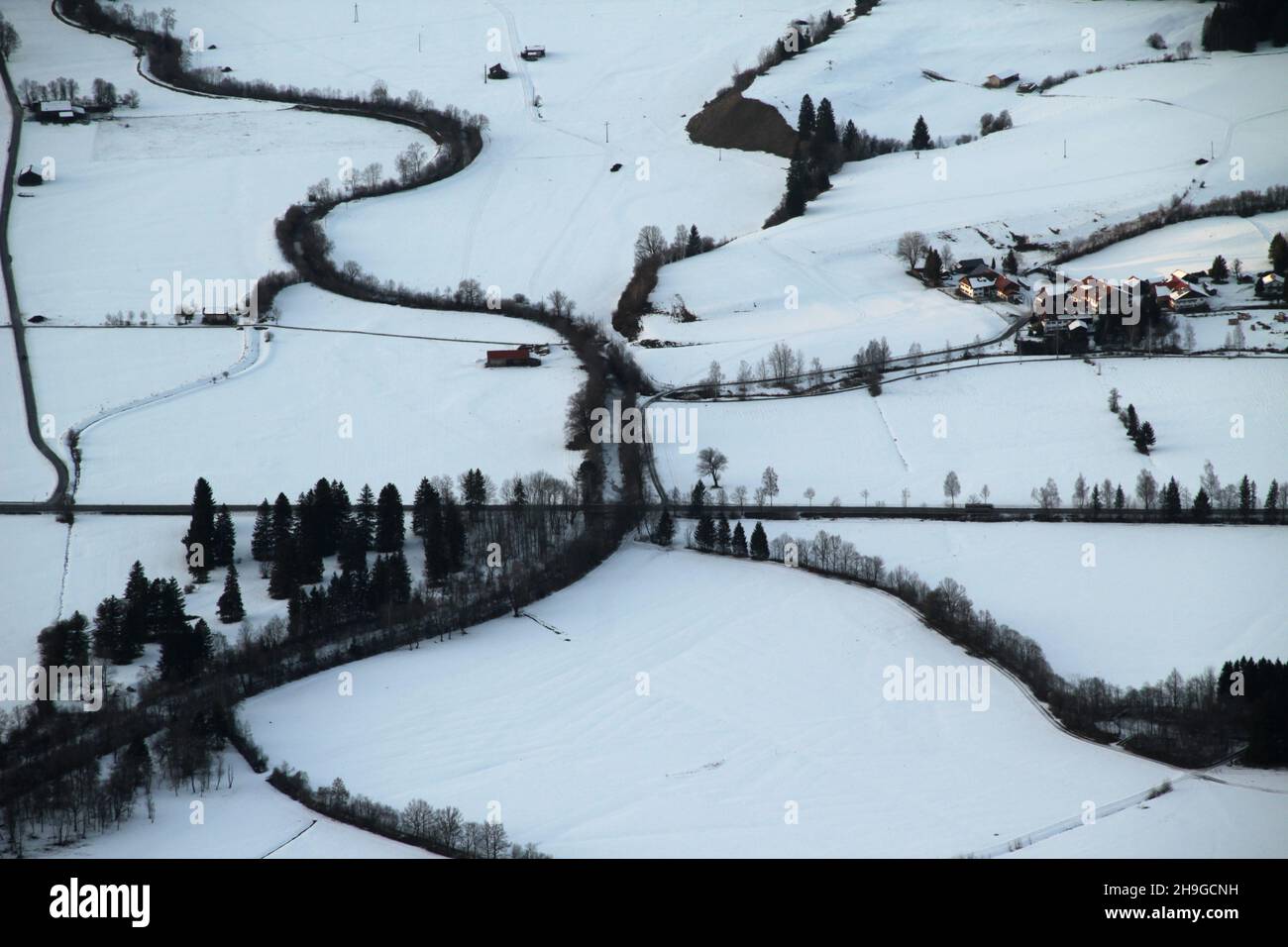 Aerial view of the snow-capped Alps, houses, and trees Stock Photo - Alamy