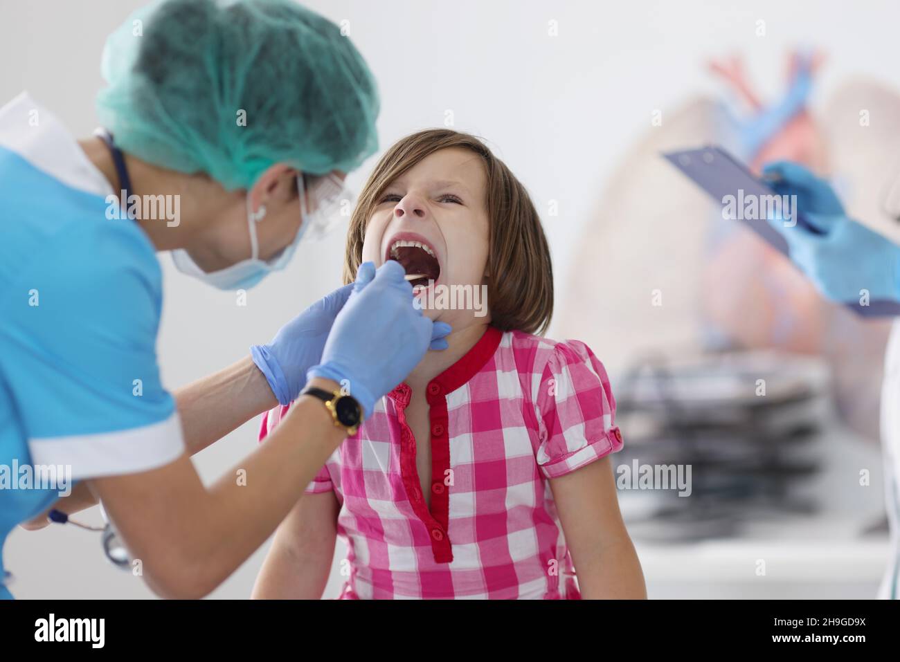 Little child open mouth for check up, hurting throat, pediatrician appointment check with tool Stock Photo