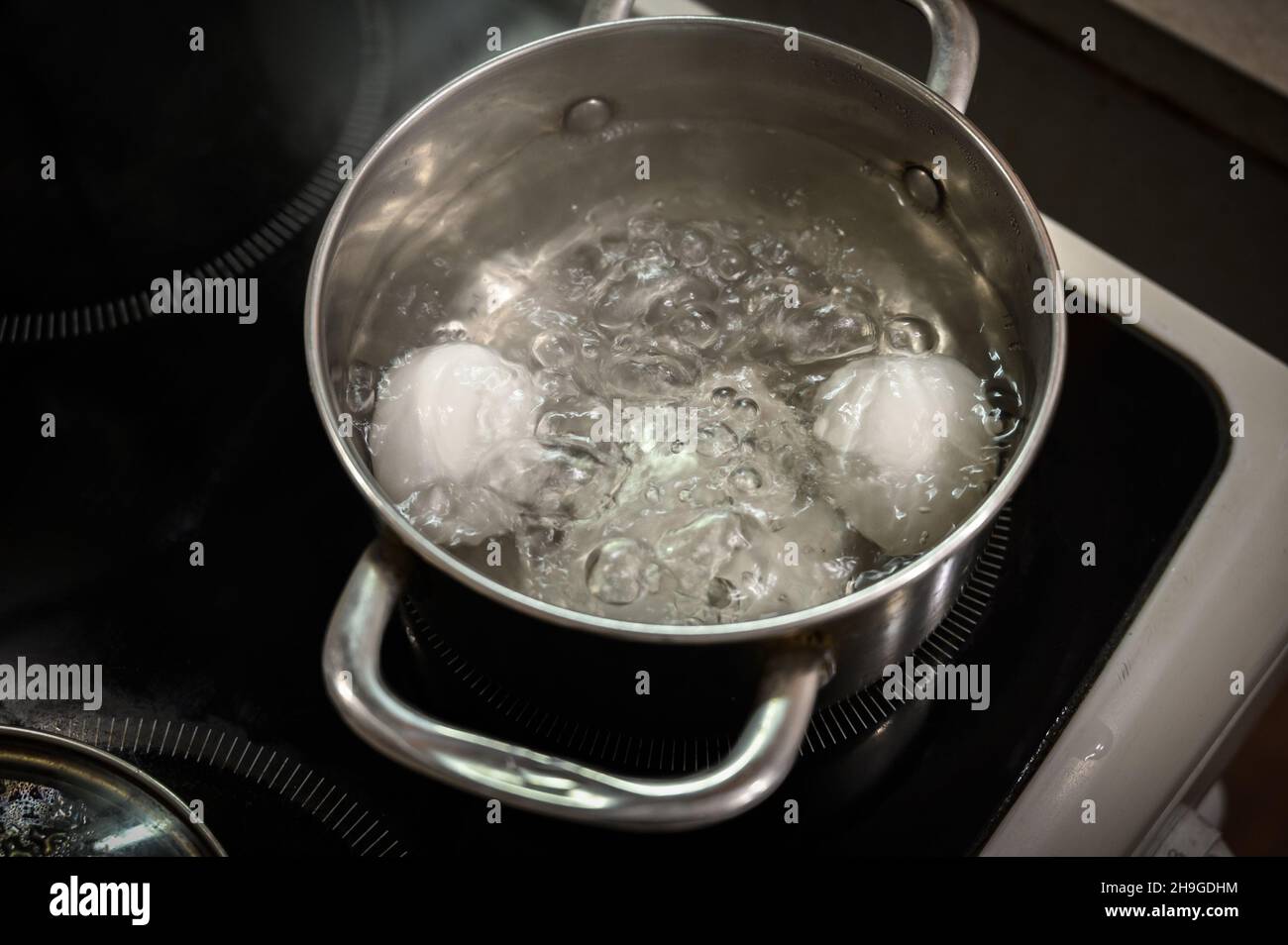 Two white eggs are boiled in a saucepan. Stock Photo