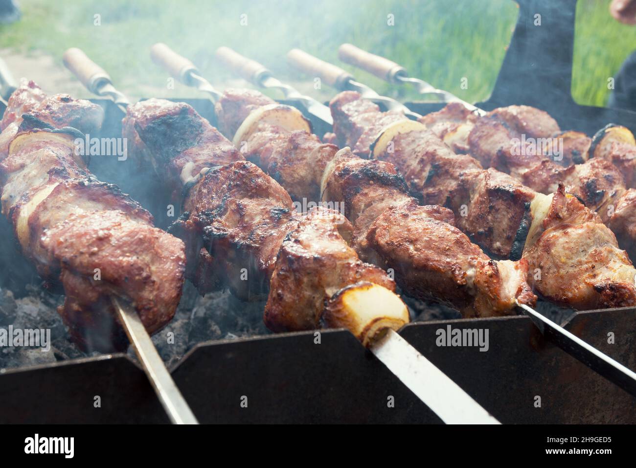 Grilling marinated shashlik on a grill. Shashlik is a form of Shish kebab  popular in Eastern, Central Europe and other places. Shashlyk meaning skewer  Stock Photo - Alamy