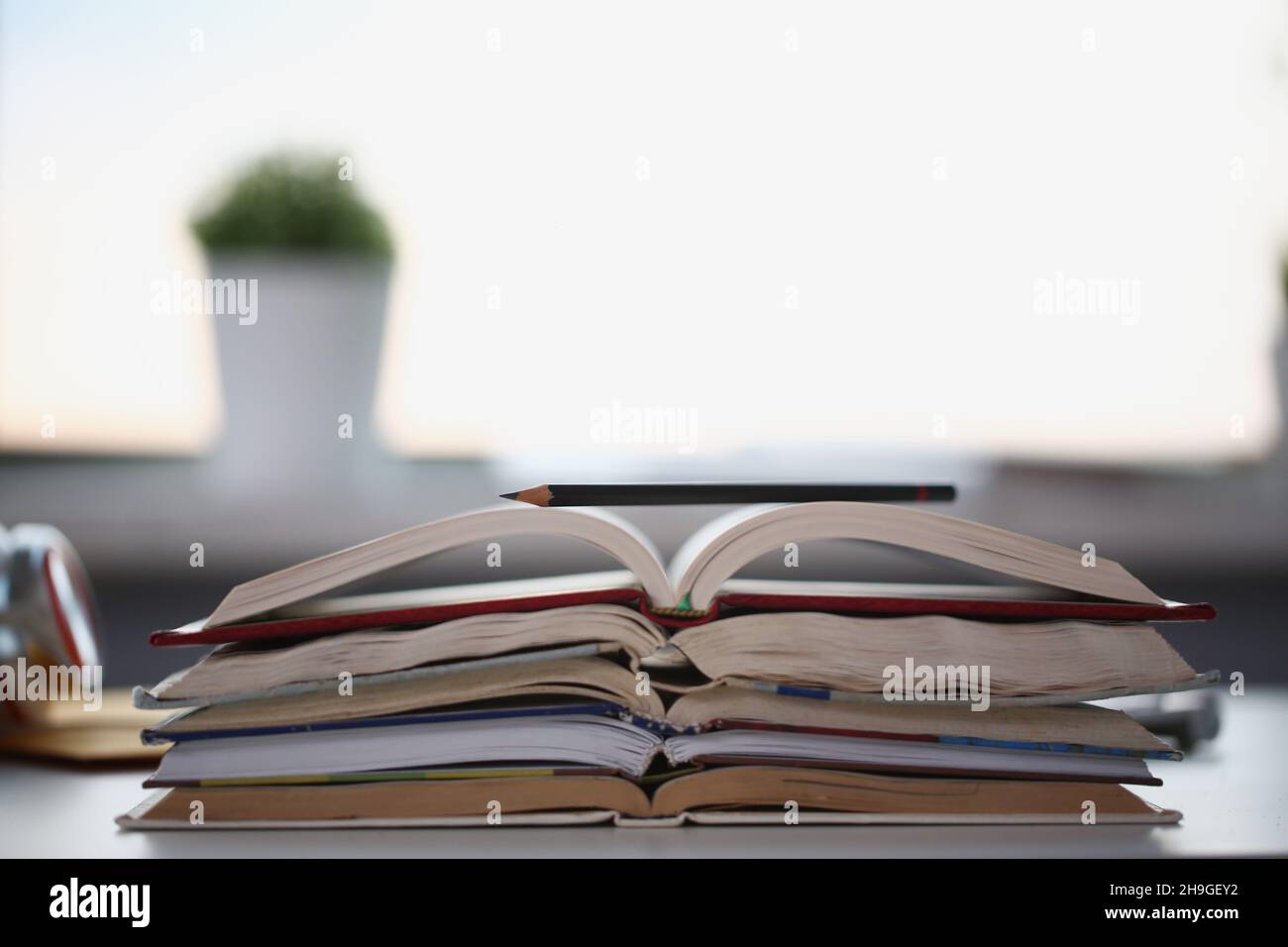 Stack of books lay on table, undone homework tasks or things to learn at home Stock Photo