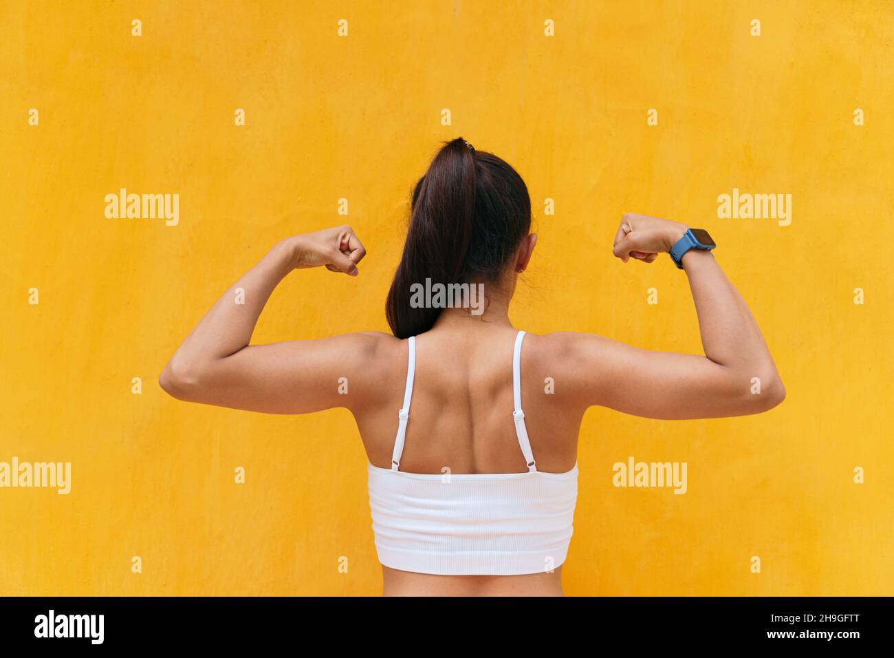 Mestizo woman flexing her muscles in the open air Stock Photo