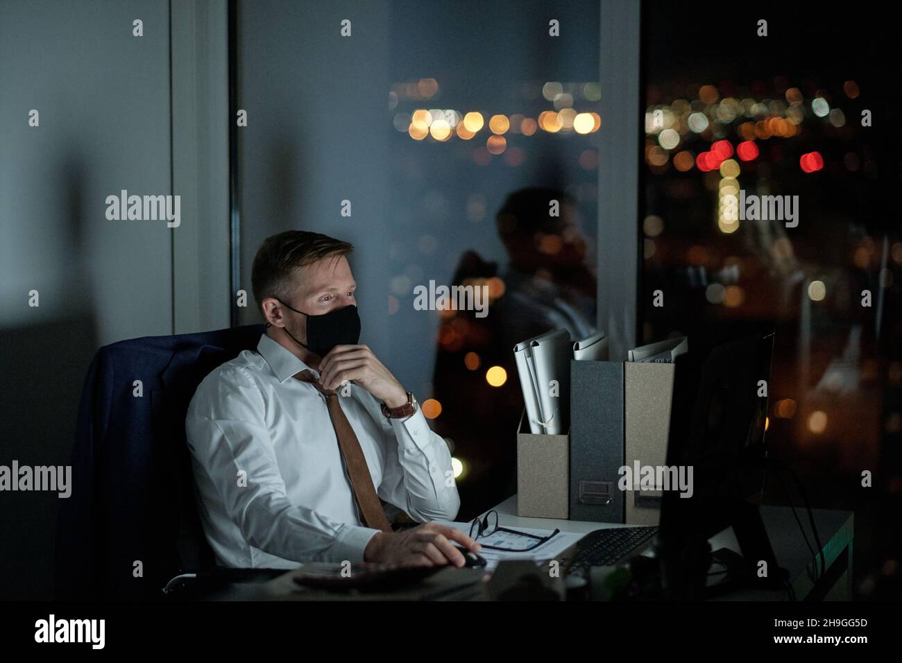Young White Collar Worker In Protective Mask Looking At Computer Screen Young White Collar Worker In Protective Mask Looking At Computer Screen