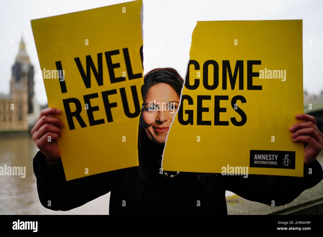 An Amnesty International campaigner, wearing a Priti Patel mask, tears up a 'Refugees Welcome' placard opposite Parliament in London as the Nationality and Borders Bill is to be debated today. Picture date: Tuesday December 7, 2021. Stock Photo