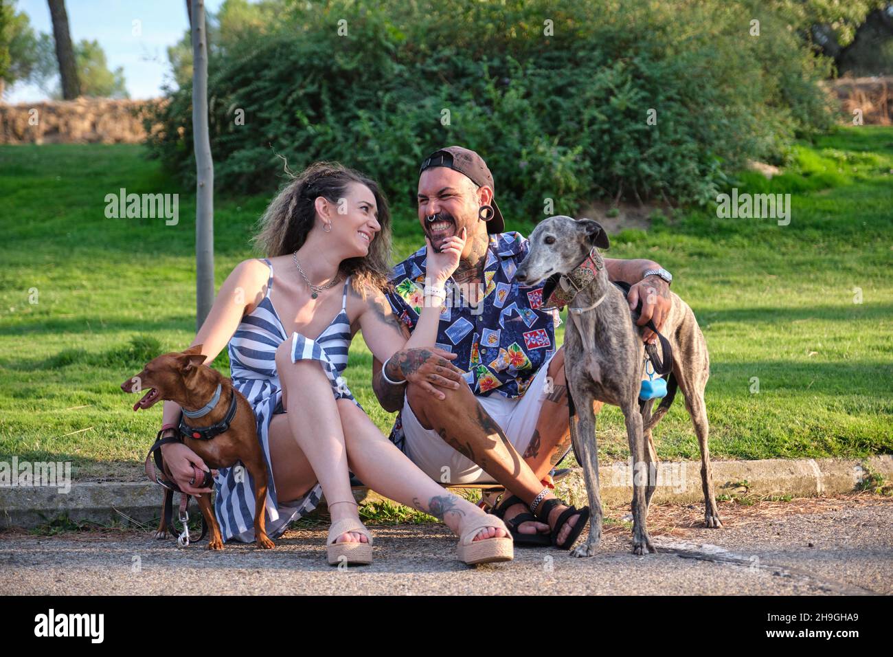 Young tattooed couple hugging and sitting with their dogs Stock Photo ...