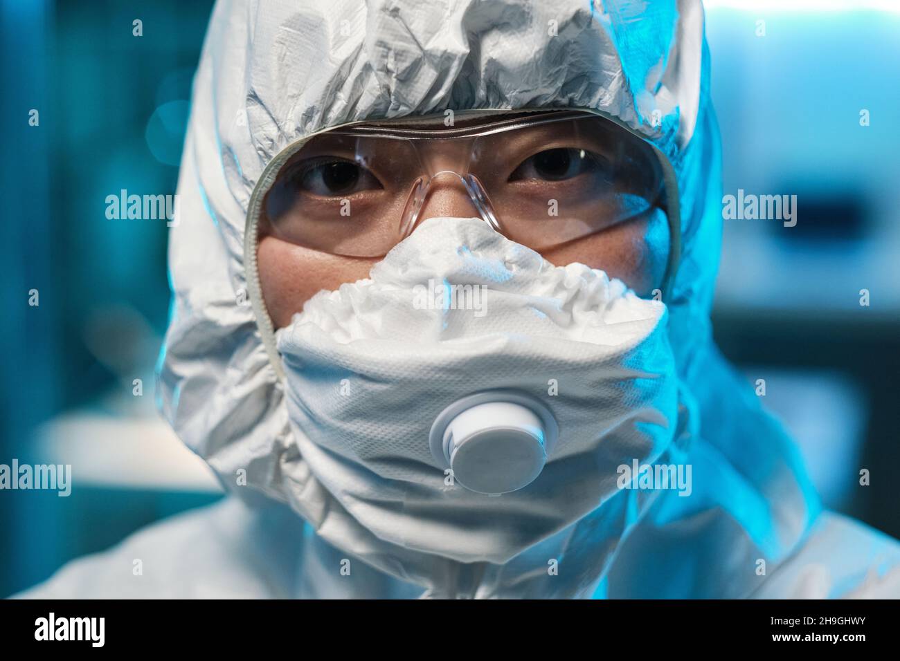 Face of young Asian female scientist in protective respirator, eyeglasses and coveralls Stock Photo