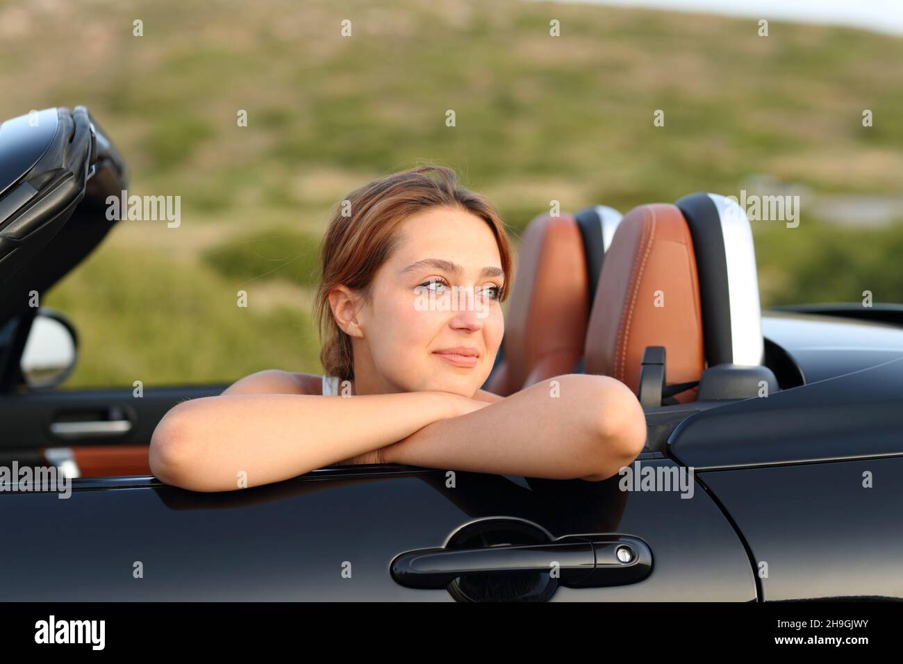 Satisfied owner looking away in a cabriolet car in the mountain Stock Photo