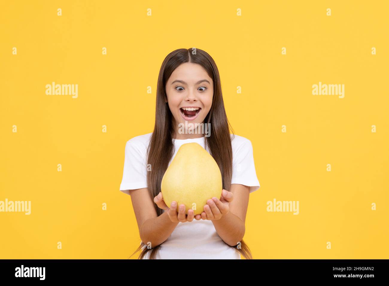 happy child girl hold big citrus fruit of yellow pummelo or pomelo full