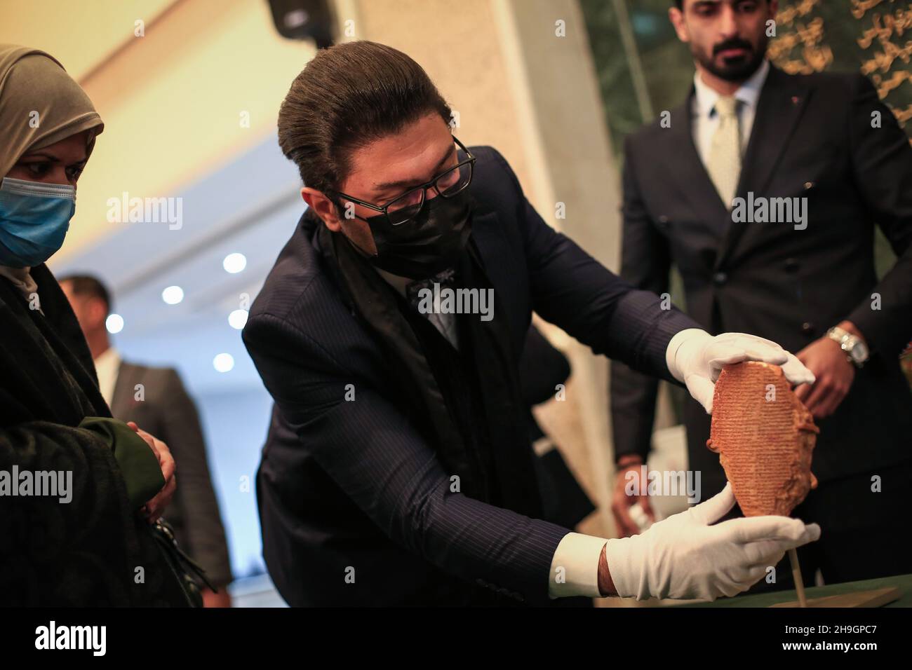 Baghdad, Iraq. 07th Dec, 2021. An employee displayes The Gilgamesh Tablet, a 3,500-year-old clay tablet that was looted from Iraq 30 years ago, at the Iraqi Ministry of Foreign Affairs after it returned home. The Mesopotamian tablet that features inscriptions depicting the story of a superhuman king from the Epic of Gilgamesh returned from the US on Tuesday, 30 years after it was looted from a museum in Iraq during the Gulf War and illegally imported into the US to be displayed at Washington's Museum of the Bible. Credit: Ameer Al Mohammedaw/dpa/Alamy Live News Stock Photo