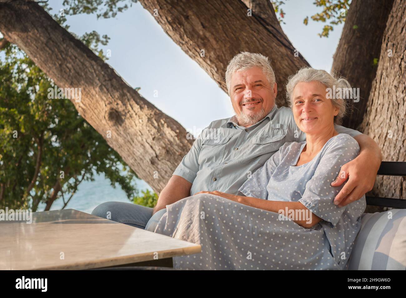 Elderly couple on vacation in a restaurant overlooking the sea. Man and woman sitting at a table Stock Photo