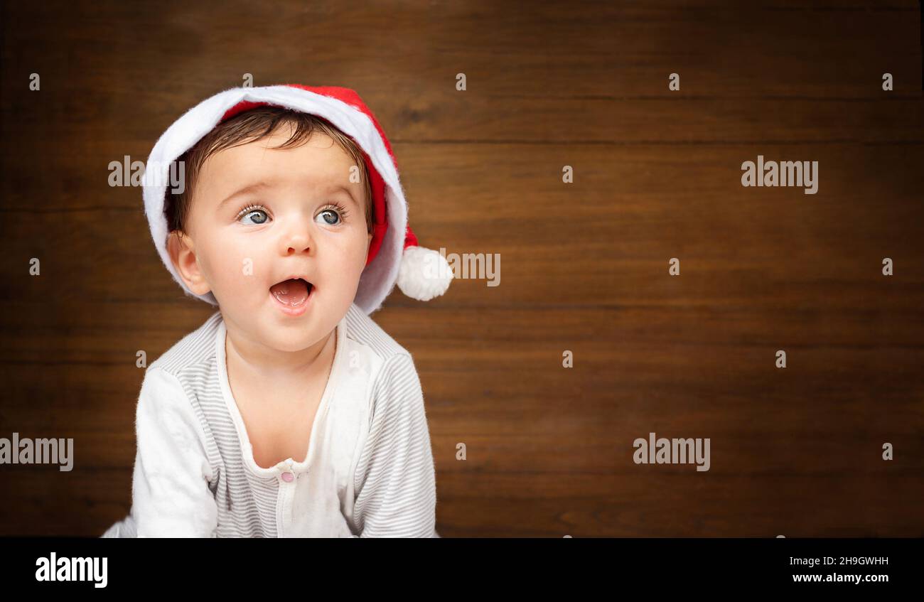 christmas baby portrait on wooden background. child in santa hat smiling Stock Photo