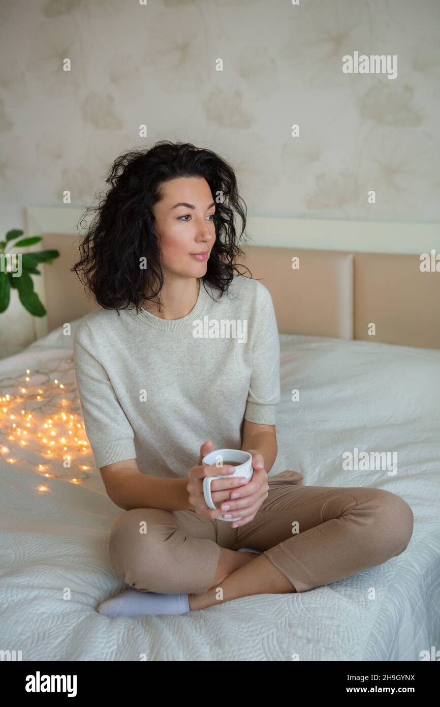 Woman holding a cup of tea in bed. Stock Photo