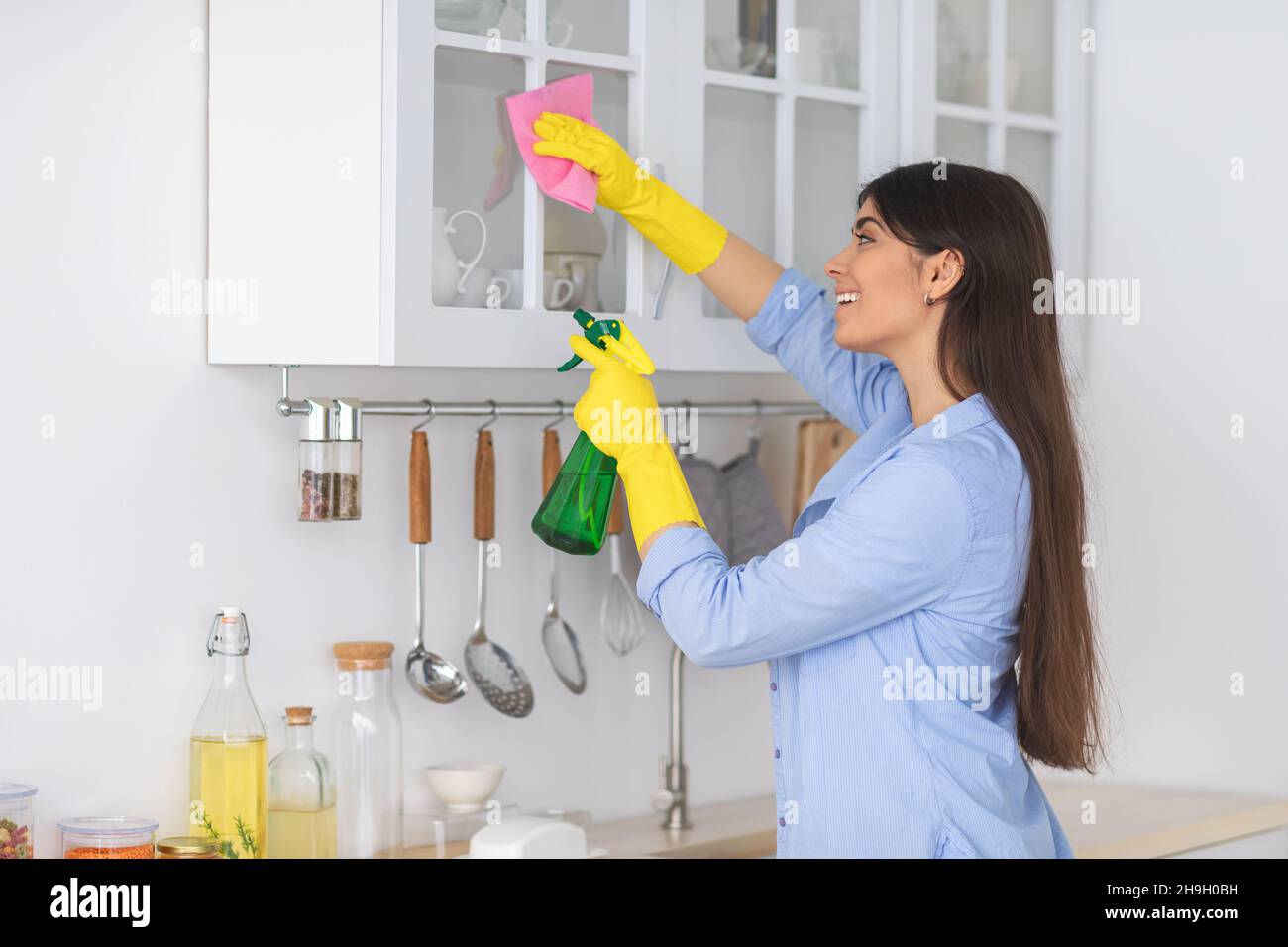 Young woman cleaning shelfs at home at kitchen Stock Photo