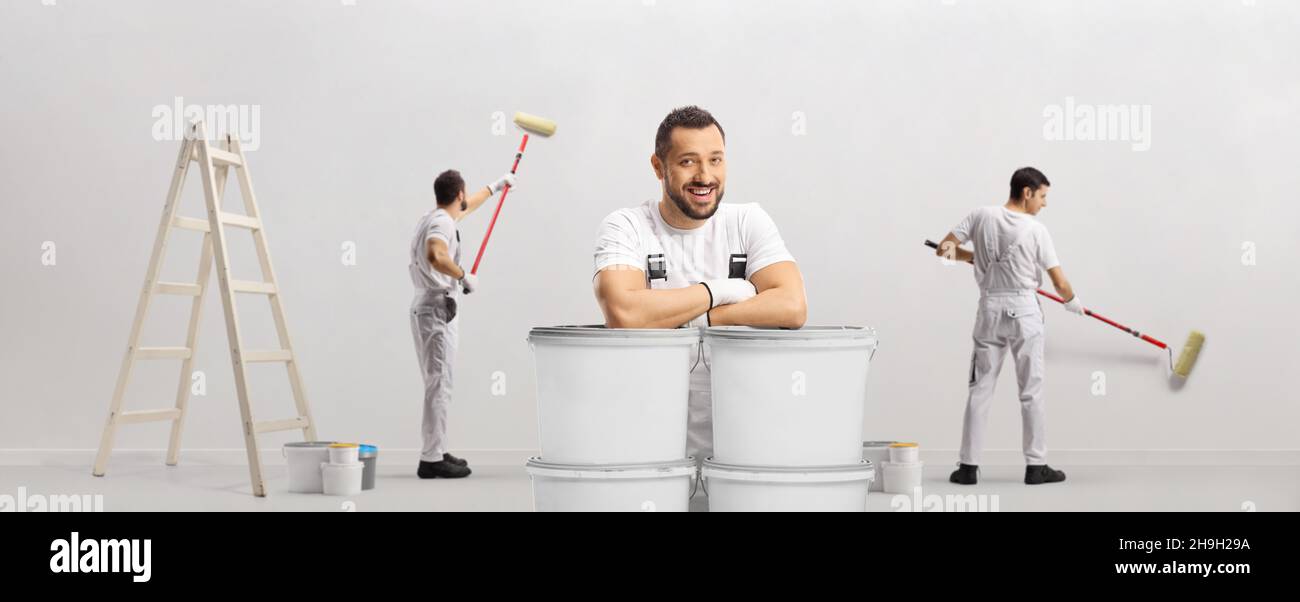 House decorators painting a wall and one painter leaning on buckets