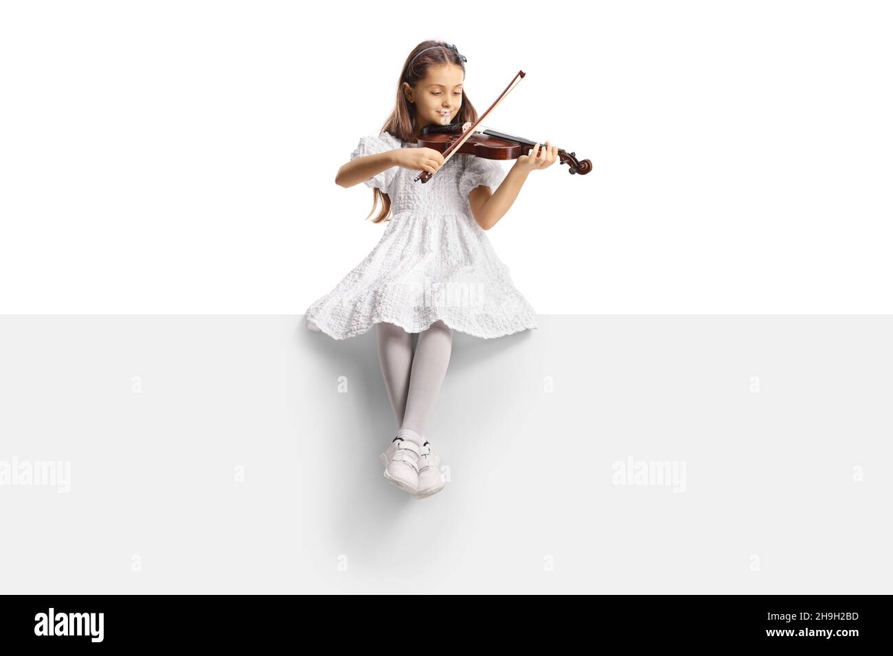 Full length portrait of a girl in a white dress sitting on a blank ...