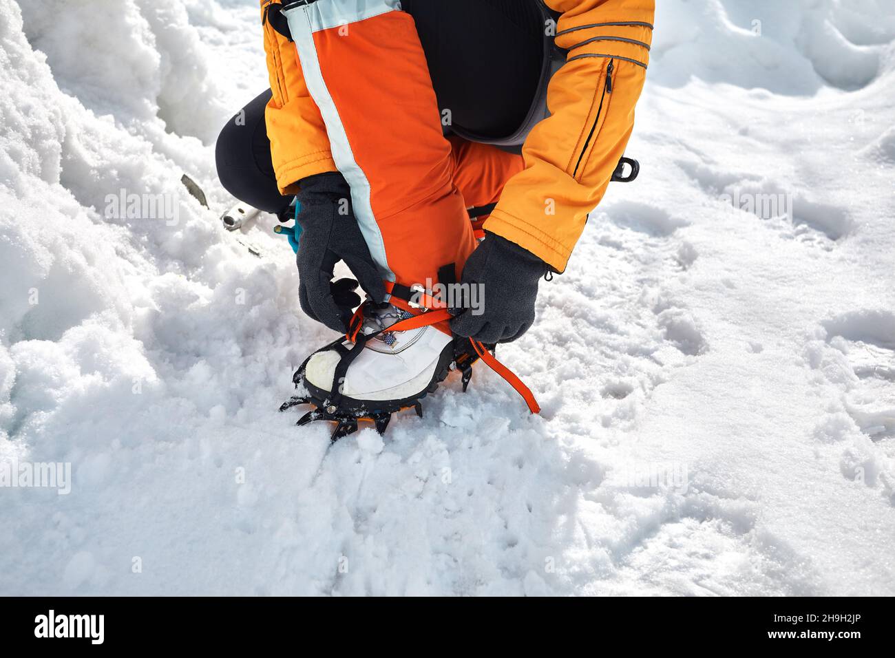 Woman climber in orange gaiters with ice axe near frozen waterfall in the mountains in Almaty, Kazakhstan Stock Photo