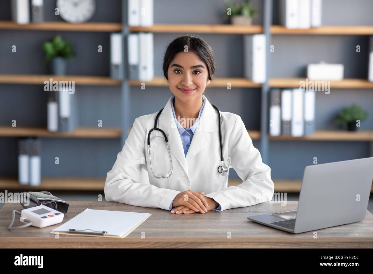 Cheerful millennial indian female doctor in white coat work at ...