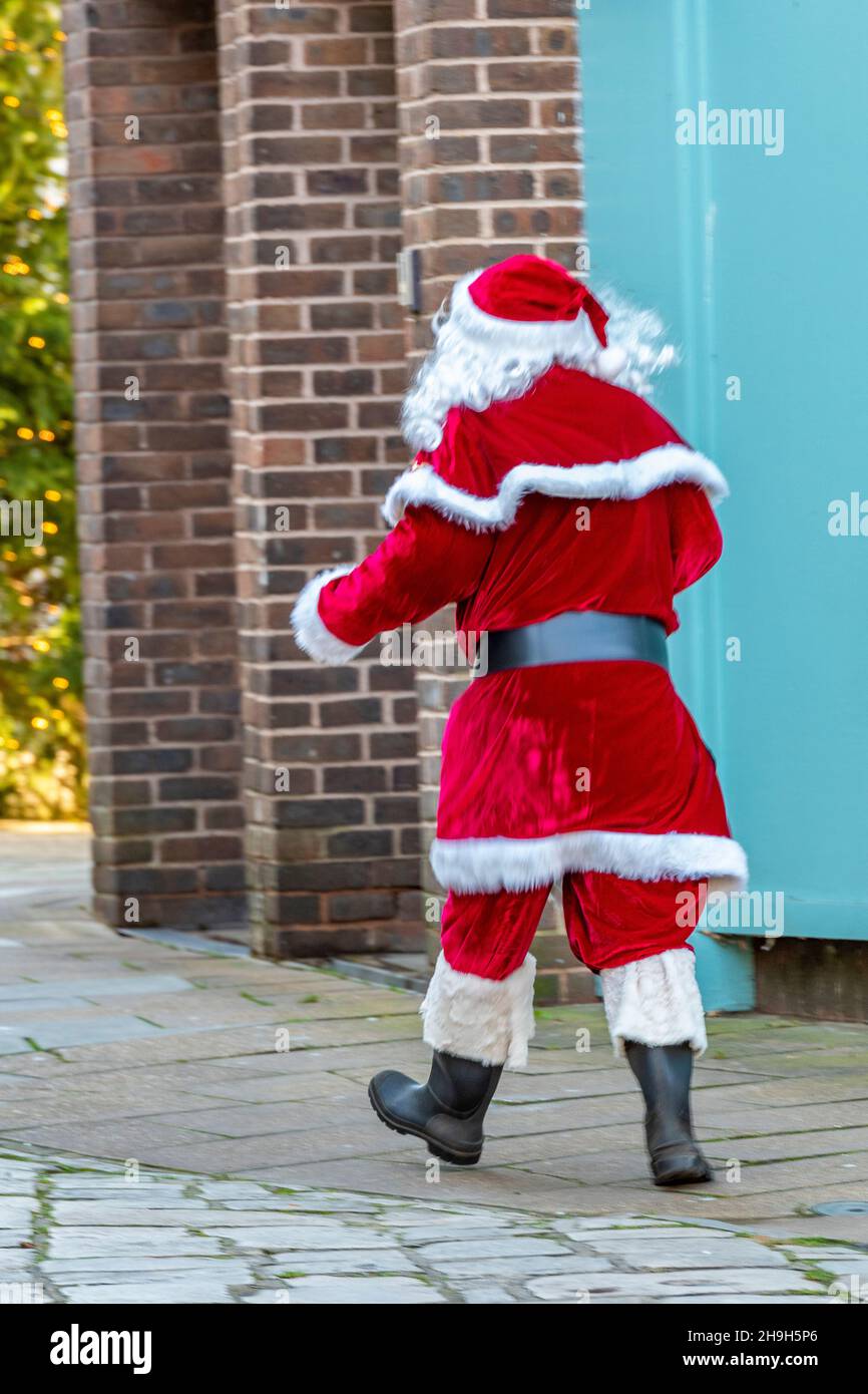 man dressed in santa claus or father christmas costume, santa walking through town, father christmas outfit worn by man walking through city centre. Stock Photo