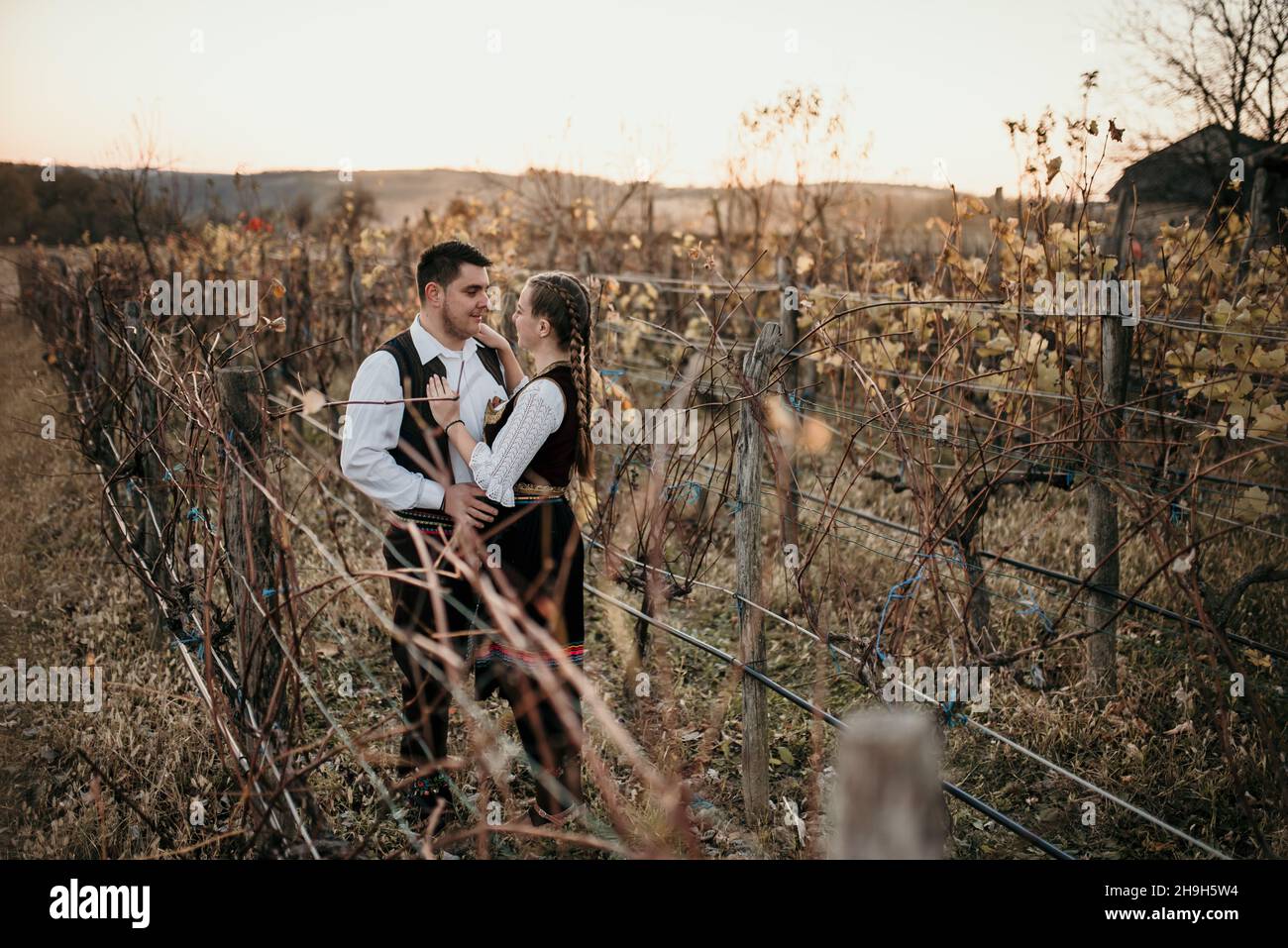 Young happy beautiful couple in traditional Serbian costumes looking at each other and holding hands Stock Photo