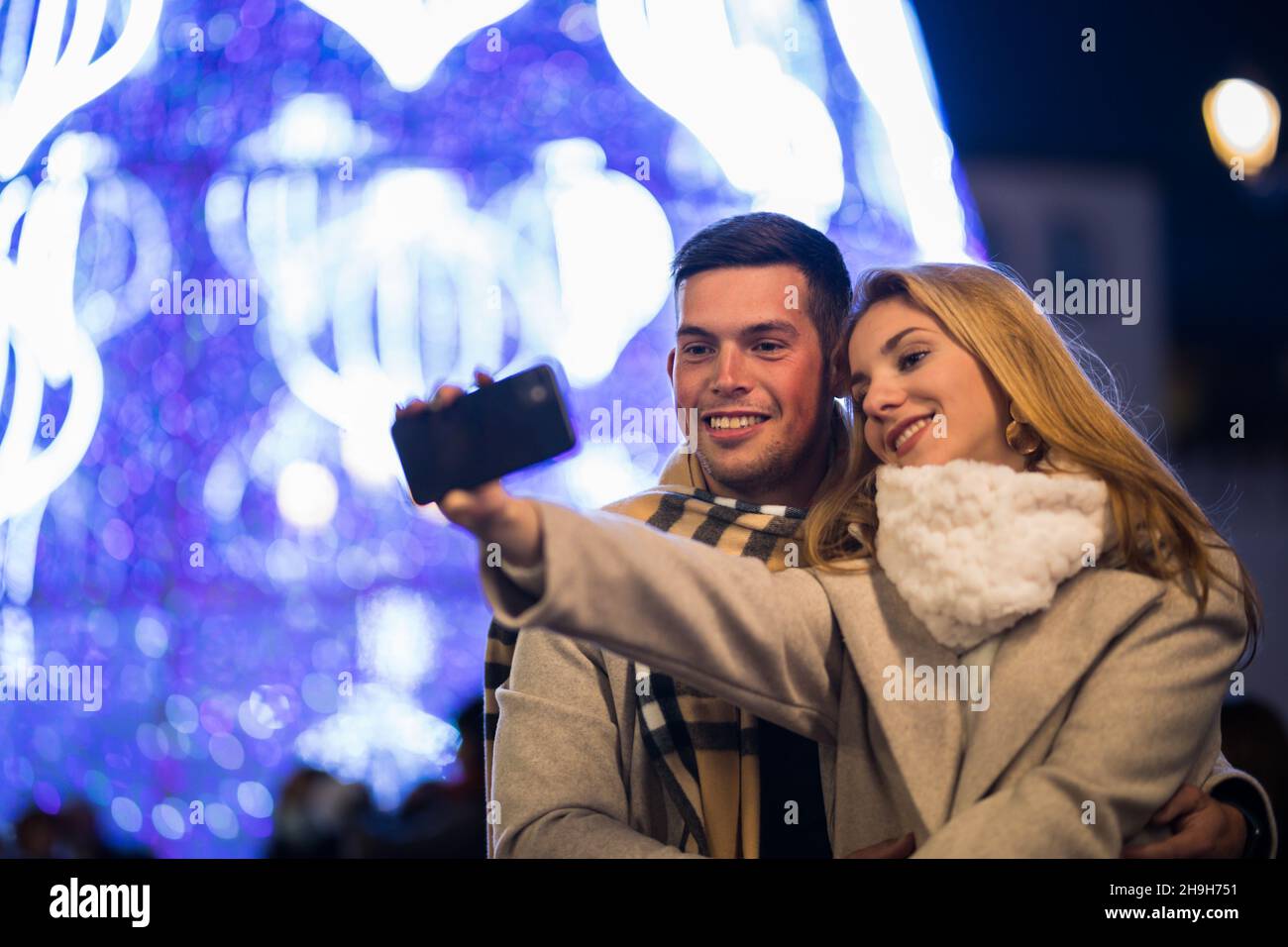 Young couple taking a selfie on the street at christmas Stock Photo