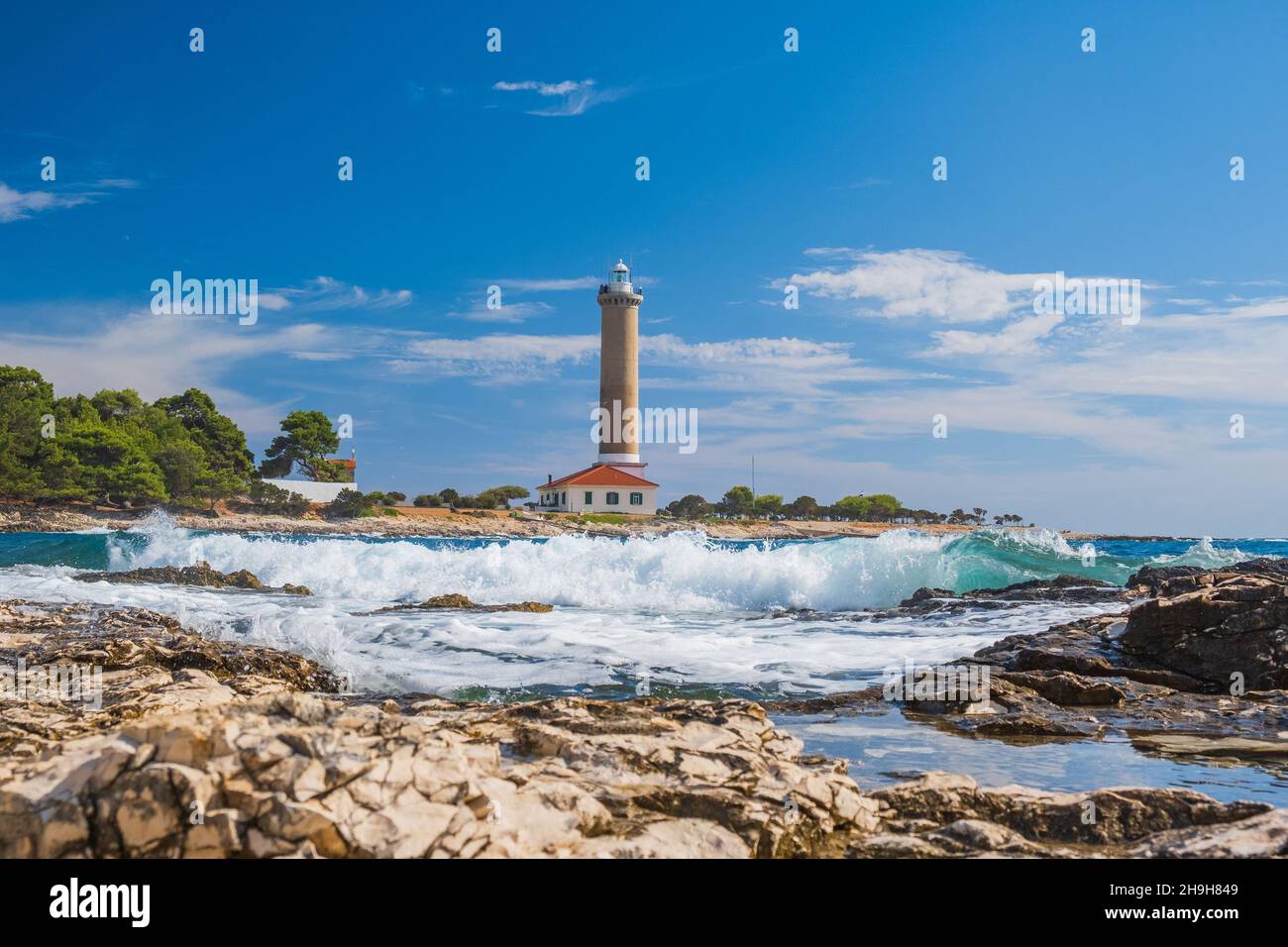Lighthouse of Veli Rat on the island of Dugi Otok, Croatia, beautiful seascape and rocks in foreground Stock Photo
