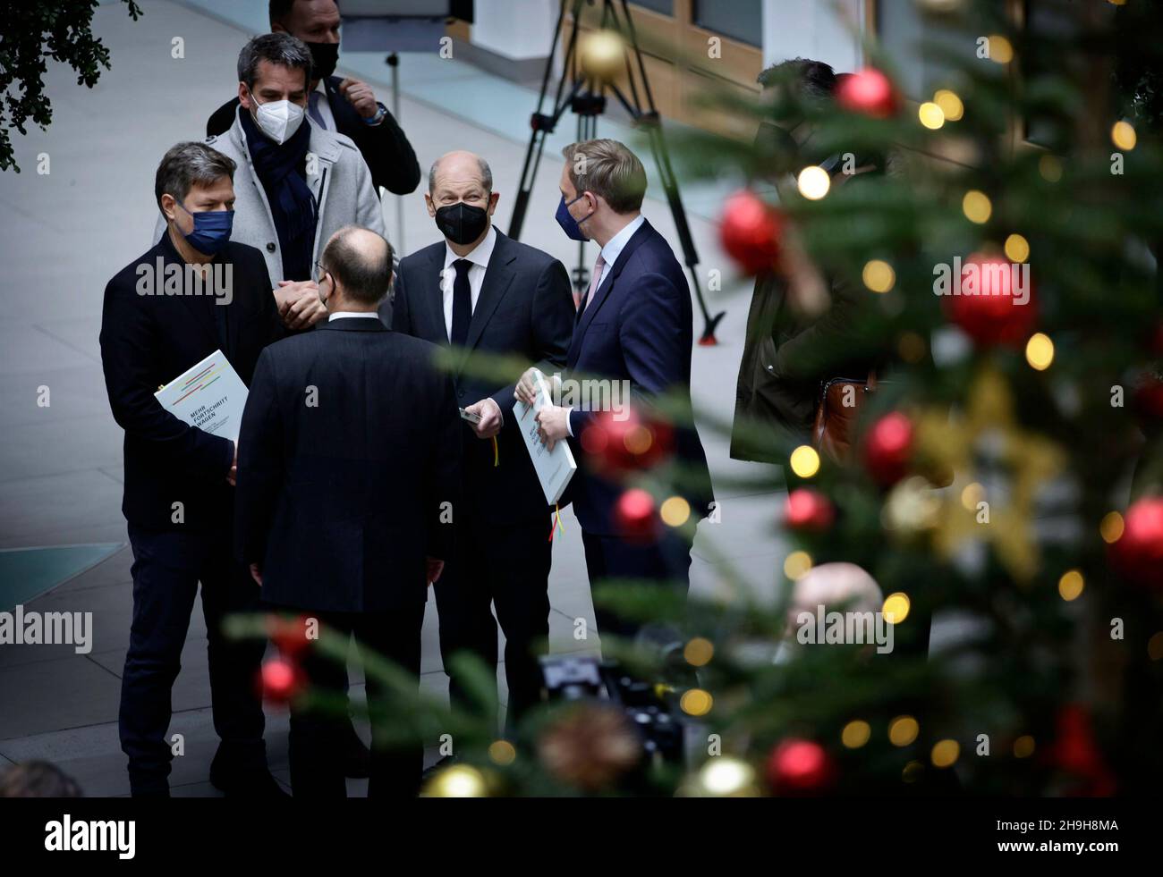 From left to right: Robert Habeck, designated Federal Minister for Economic Affairs and Climate Protection and Vice Chancellor, Olaf Scholz, designated Federal Chancellor, and Christian Lindner, designated Federal Minister of Finance, recorded in front of a Weihaftertsbaum in the house of the Federal Press Conference. Berlin, December 7th, 2021 Stock Photo