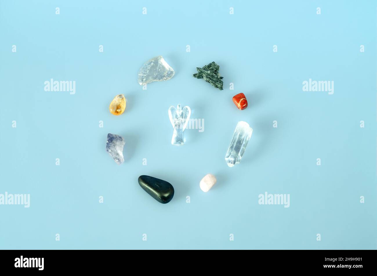 Minimalist flat lay of healing crystals circle with angel in the middle on blue background Stock Photo