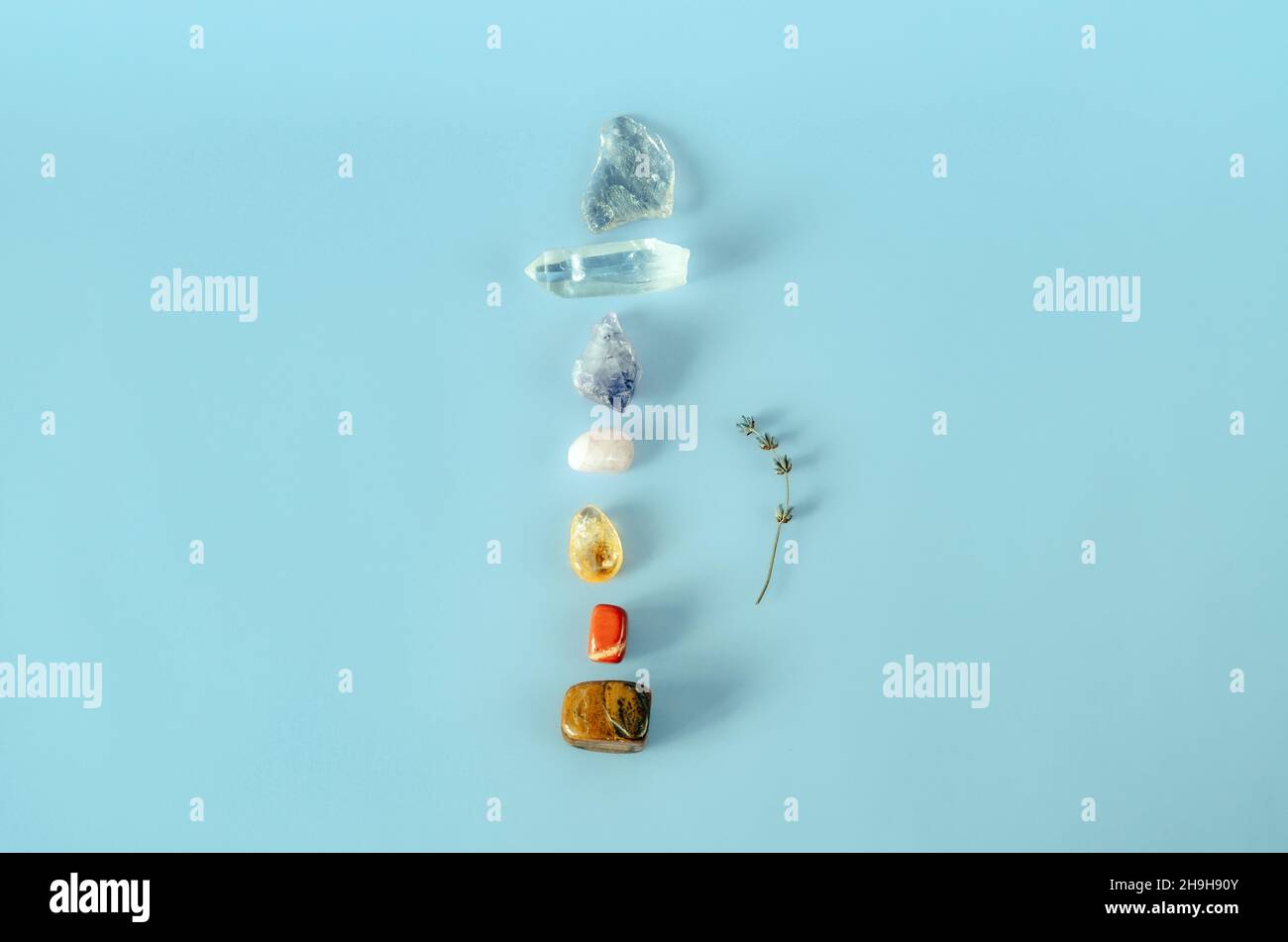 Minimalist flat lay of chakras healing crystals in a column on blue background Stock Photo