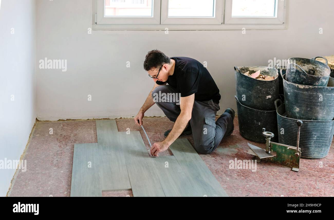 Bricklayer measuring tiles to install a floor Stock Photo