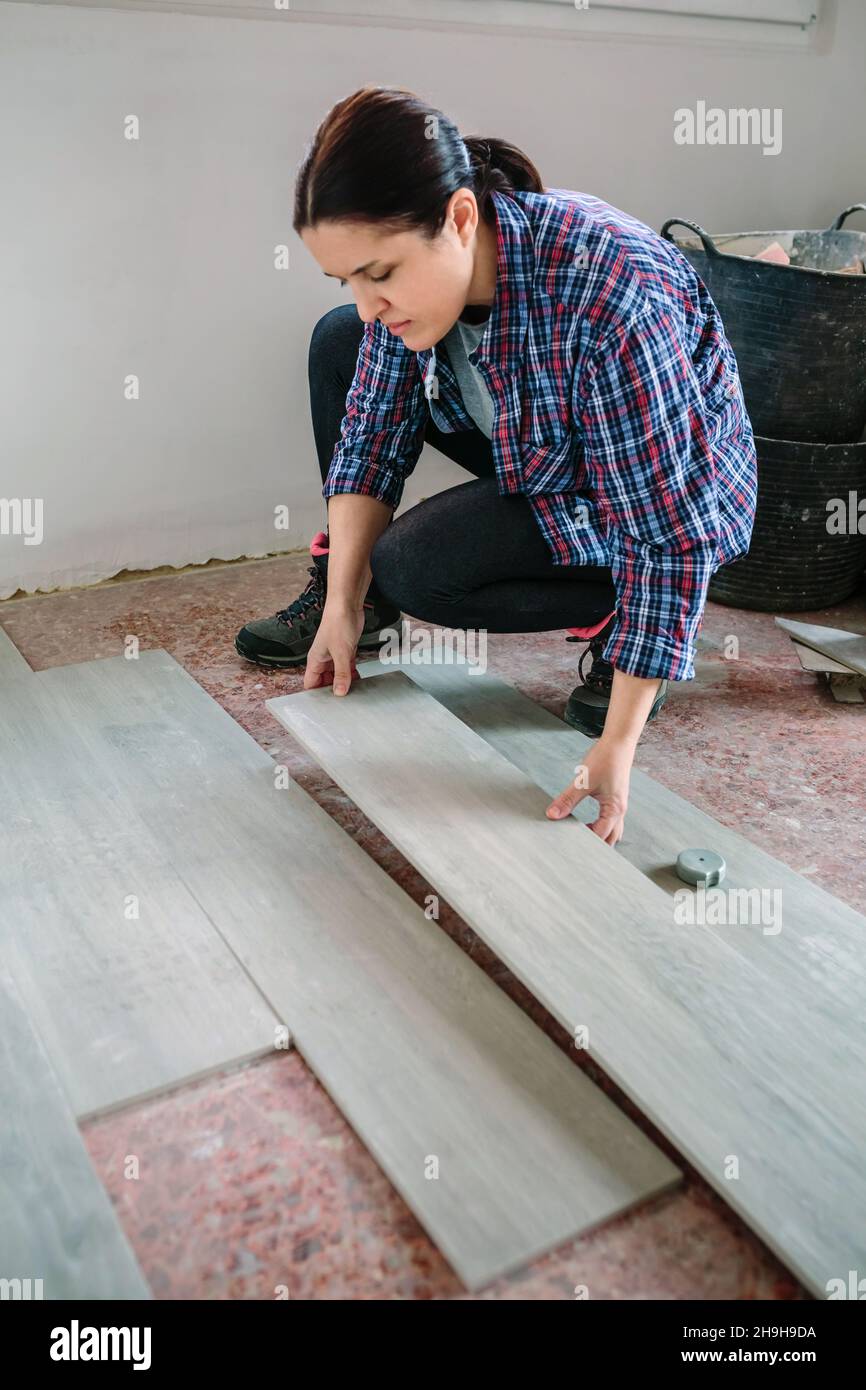 Female bricklayer placing tiles to install a floor Stock Photo Alamy