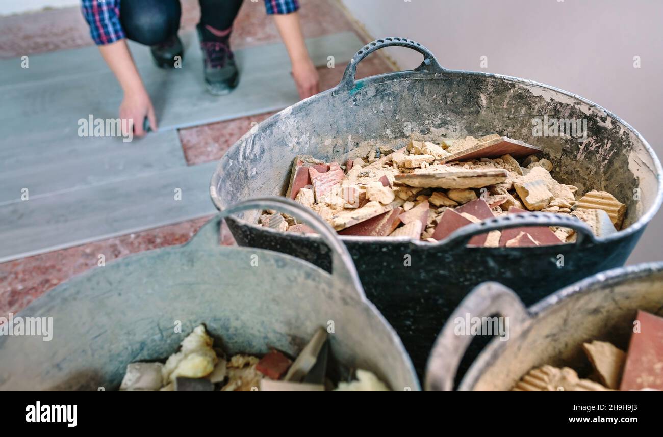 Construction rubble buckets with unrecognizable female bricklayer working in the background Stock Photo