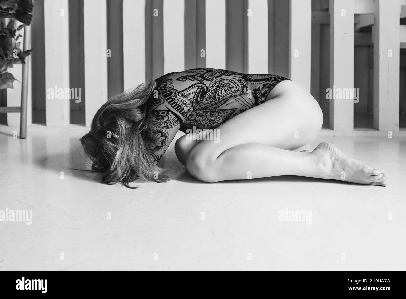 A young woman is lying on the floor in despair, depression. Mental health. lack and white Stock Photo