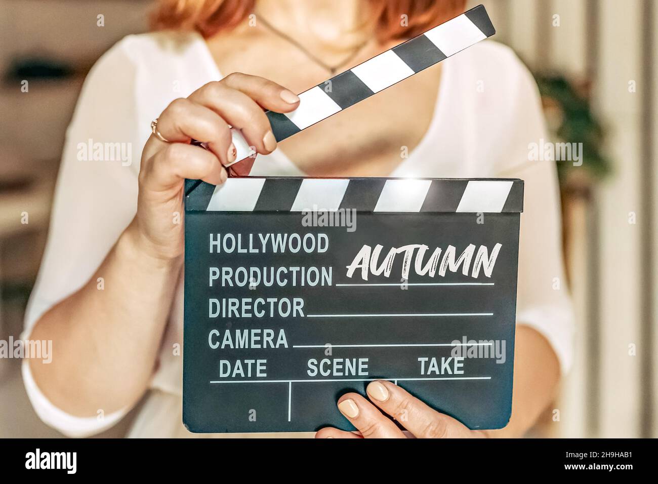 A woman in her hA woman in her hands holds a black board with a clapperboard while shooting a film, video. Cinema tablet in video production. Take, st Stock Photo