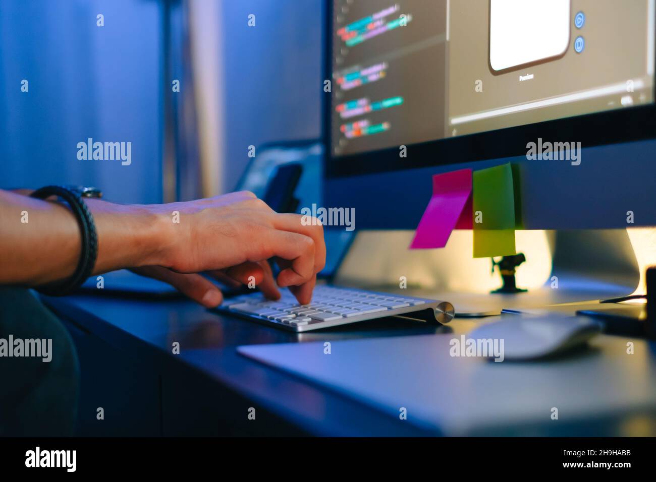 Mobile developer writes program code on a computer, typing on keyboard, programmer work in home office. Stock Photo