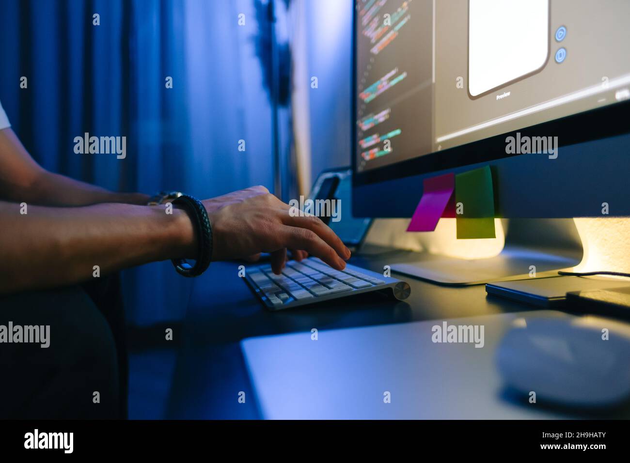 Mobile developer writes program code on a computer, typing on keyboard, programmer work in home office. Stock Photo