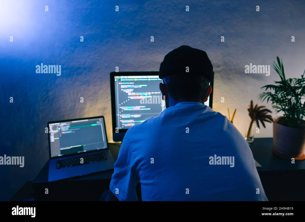 Young man mobile developer writes program code on a computer, programmer work in home office. Stock Photo