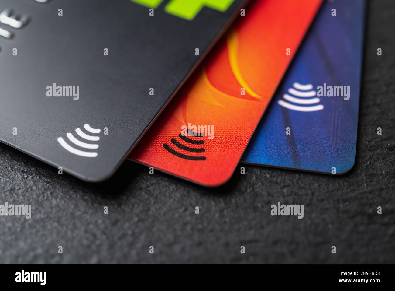 Three credit cards with contactless pay technology on a black background macro. Debit cards for money cash withdrawals. Payment for goods and services Stock Photo