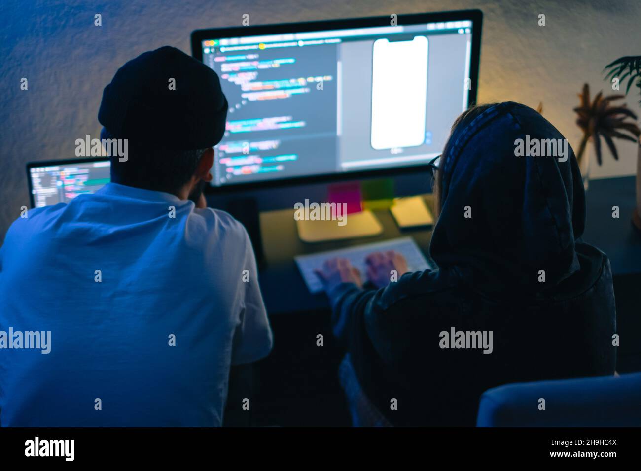 Mobile developers team writes program code on a computer, programmers work in home office. Stock Photo