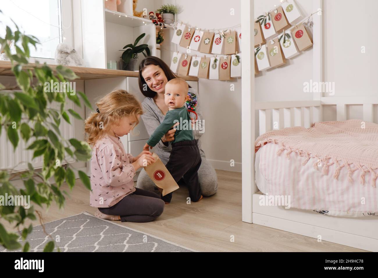 Mother with infant child having fun Christmas advent calendar tasks and gifts. Baby boy excited about festive surprise and play at home. Family Stock Photo