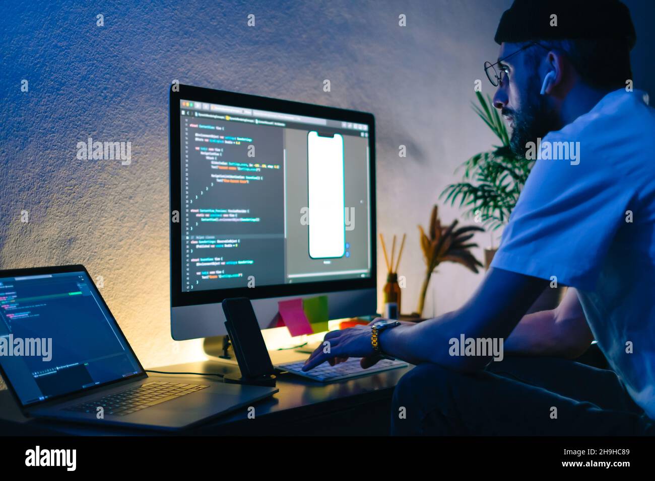 Young man mobile developer writes program code on a computer, programmer work in home office. Stock Photo