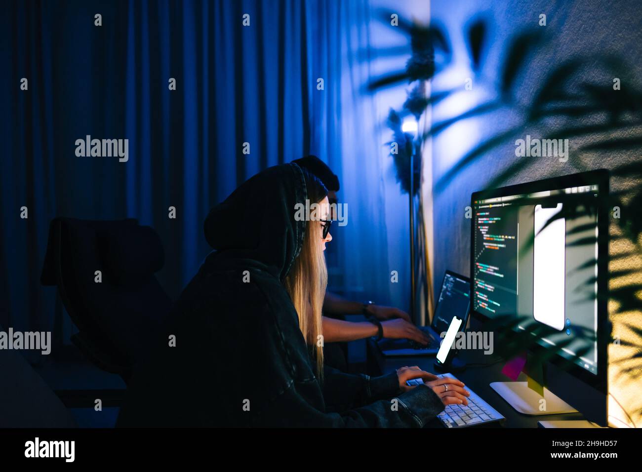 Mobile developers team writes program code on a computer, programmers work in home office. Stock Photo