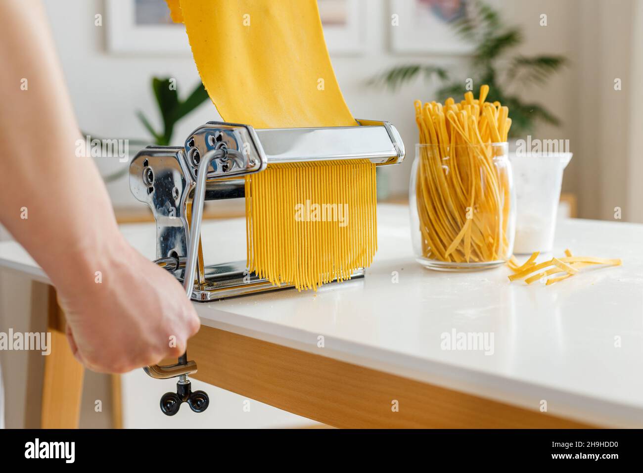 Man in apron making spaghetti with noodle cutter. Close-up pasta